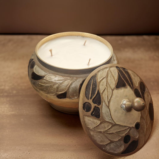 Ceramic candle holder with a lid featuring leaf patterns on a brown background