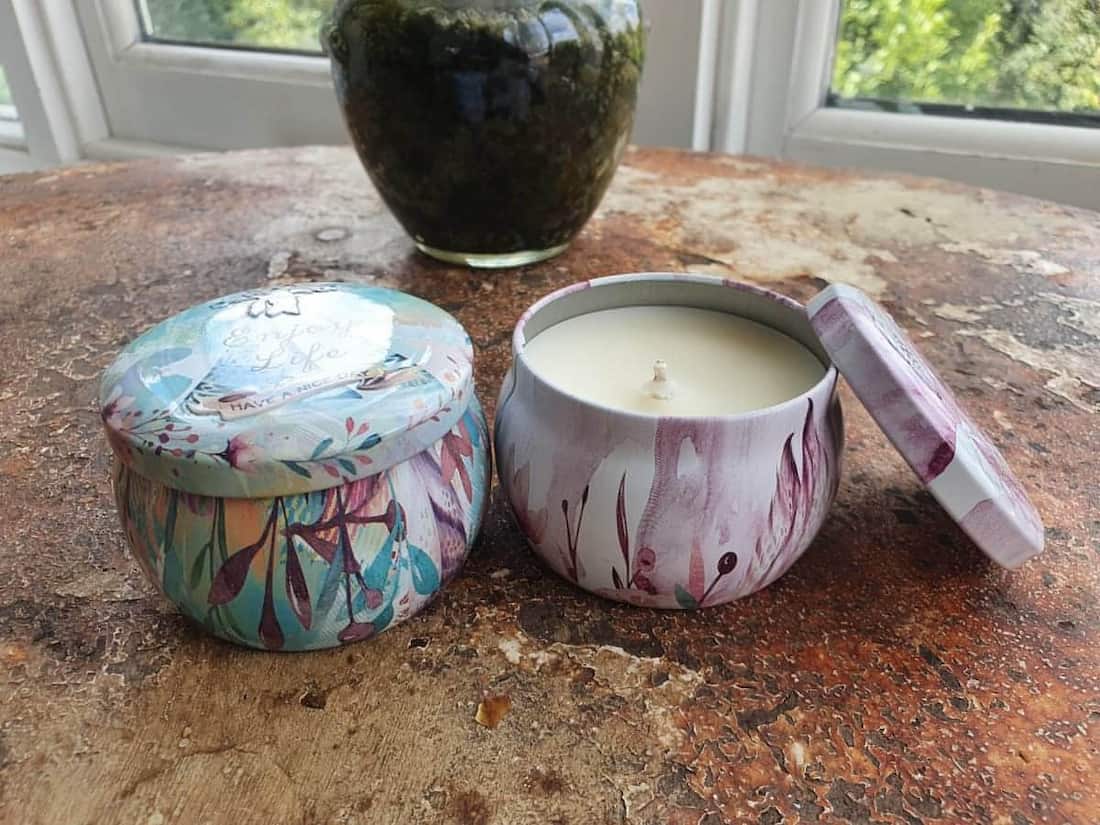 Two decorative candles with floral lids on a wooden surface.