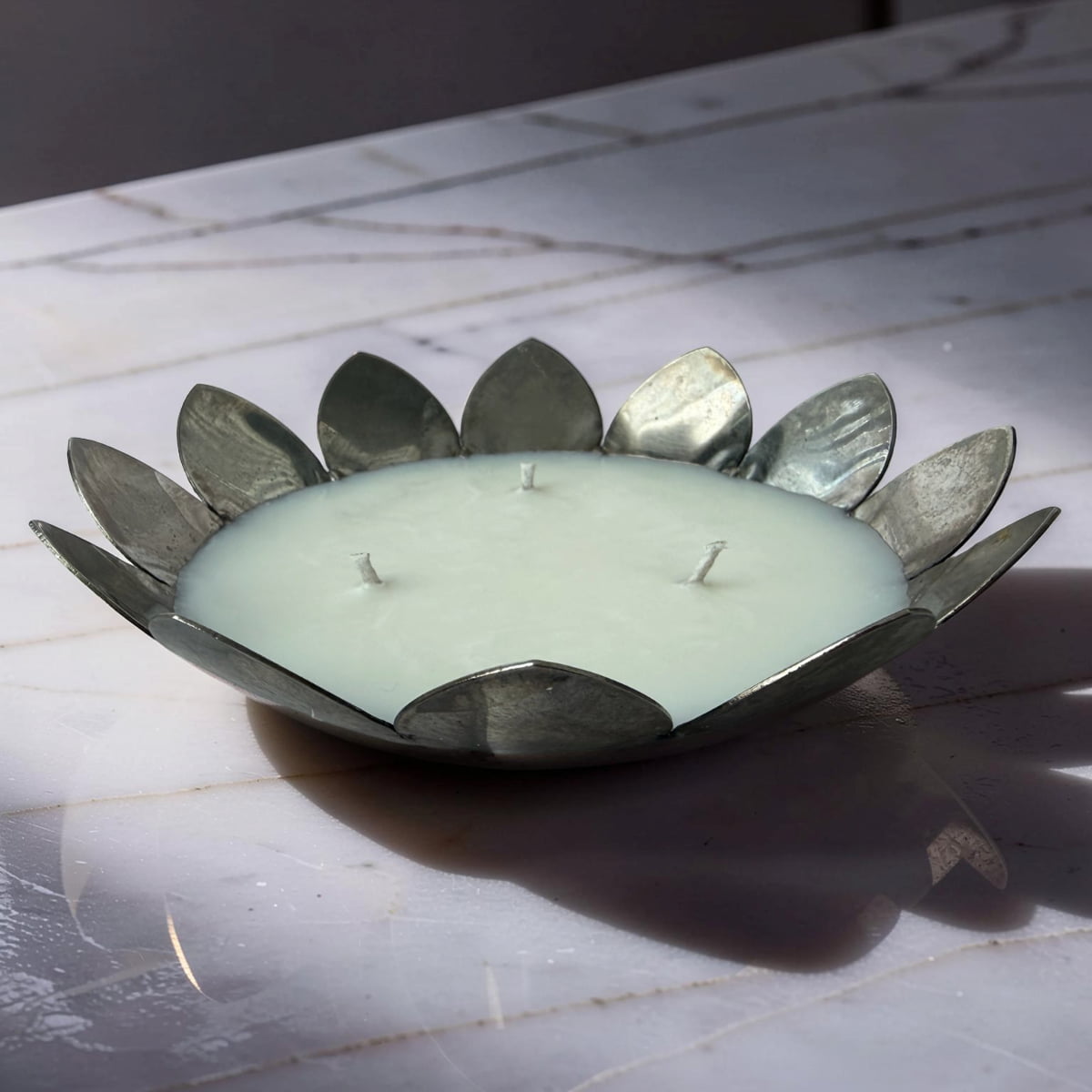 Candle in a decorative metal holder on a marble surface