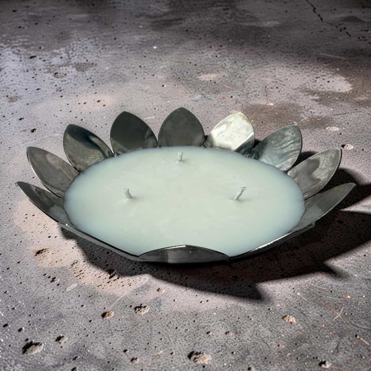 Decorative candle with metal leaf design on a concrete surface