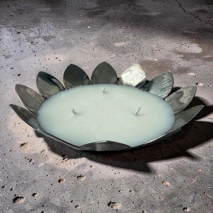 Decorative candle with metal leaf design on a concrete surface