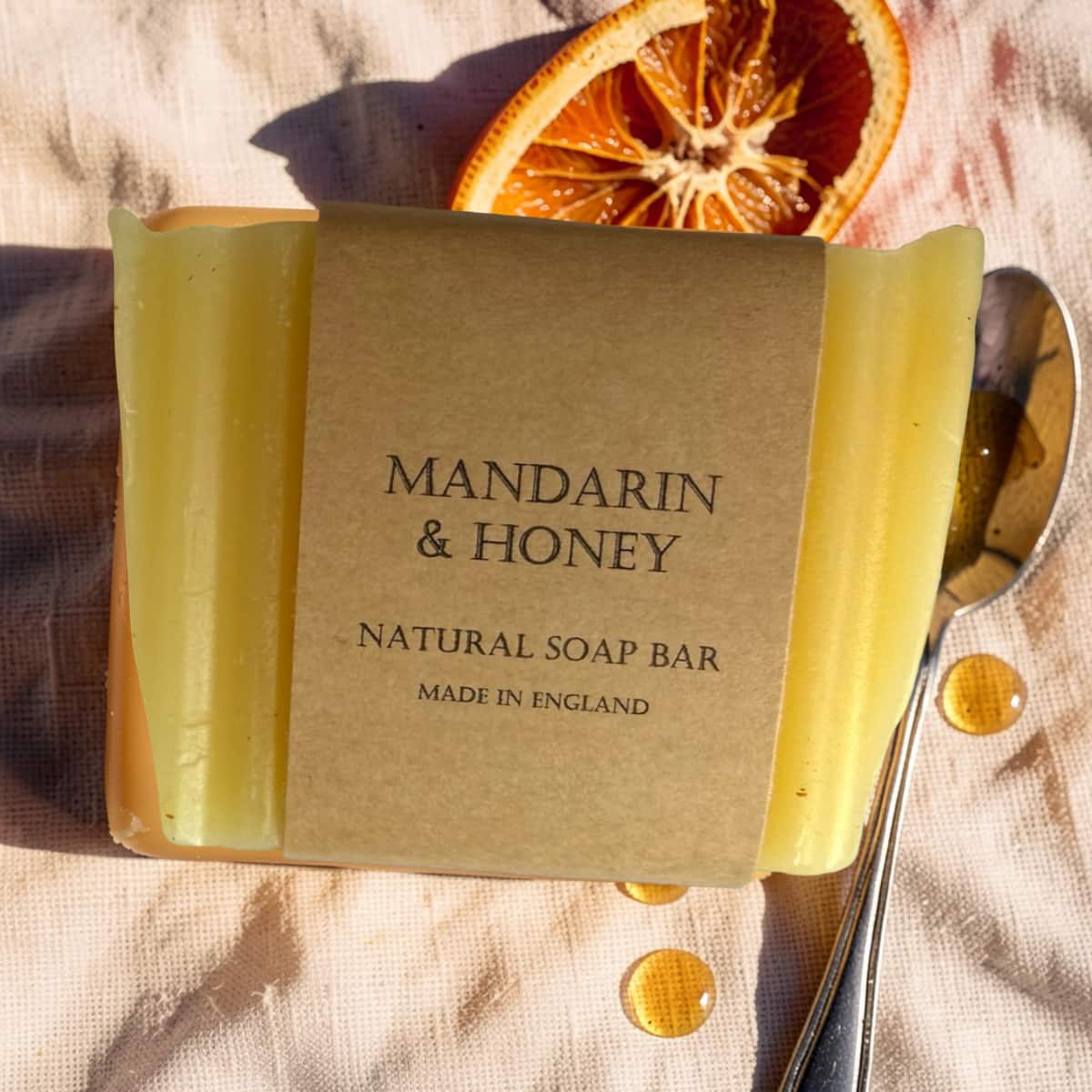 Bar of Mandarin & Honey soap with a spoon and dried orange slice on a textured surface