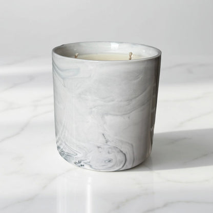Marble-patterned candle in a glass container on a white marble surface