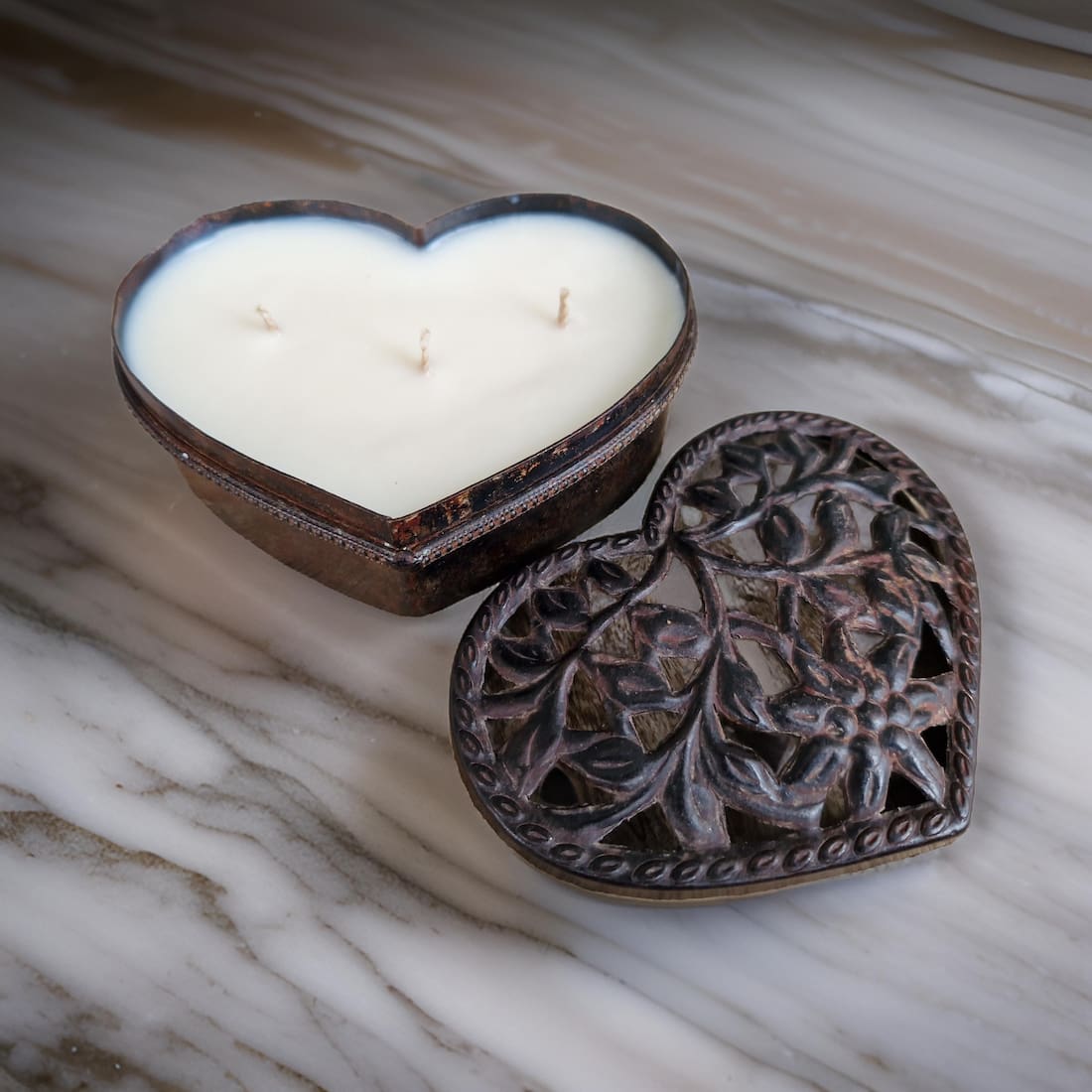 Heart-shaped candle in a decorative metal holder on a marble surface