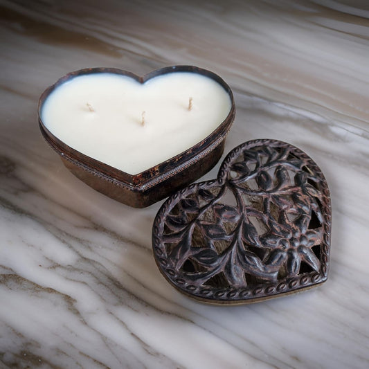 Heart-shaped candle in a decorative metal holder on a marble surface