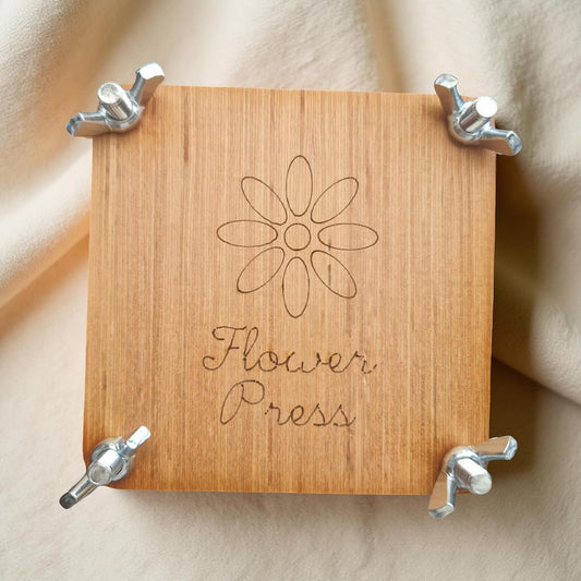 Wooden flower press with metal clamps on a beige background