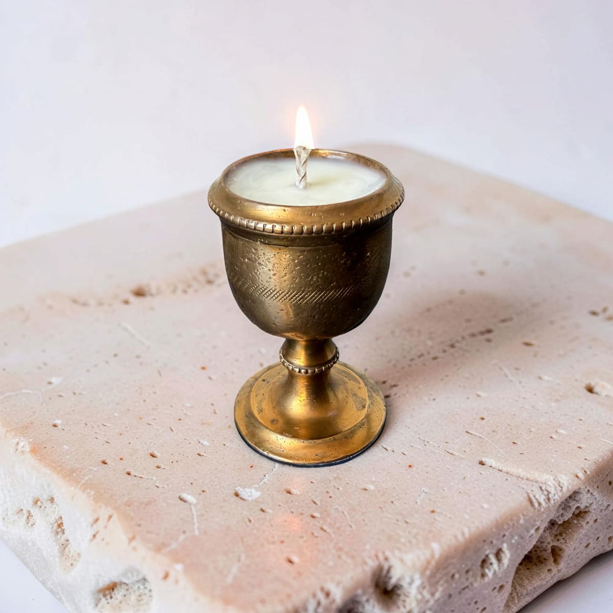 Candle in a decorative brass holder on a stone surface