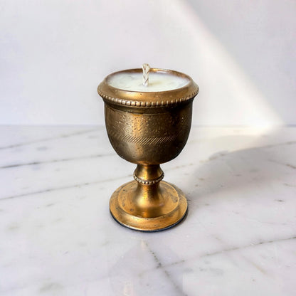 Brass candle holder with a candle on a marble surface