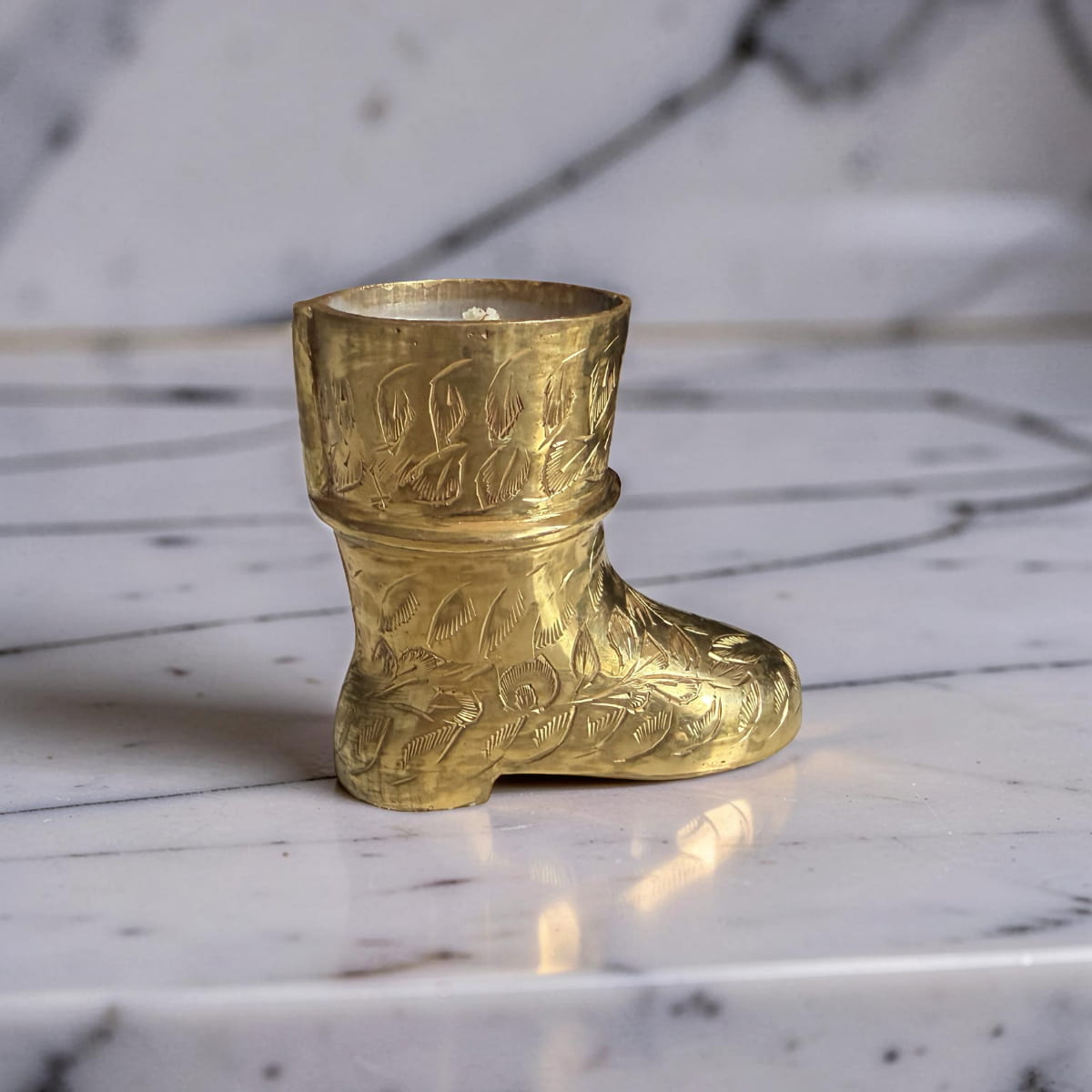 Gold boot-shaped decorative item on a marble surface
