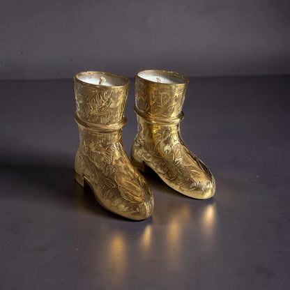 Pair of gold boots with intricate designs on a dark background