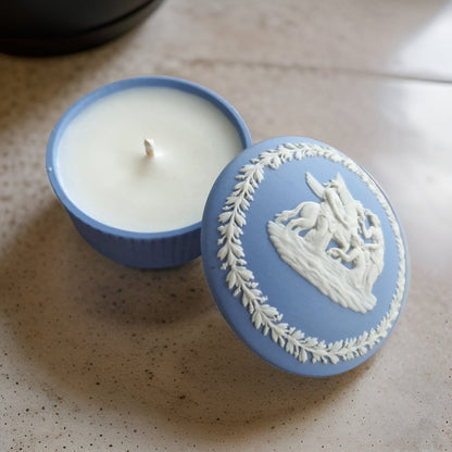 Candle in a decorative blue container with a white design on a speckled surface