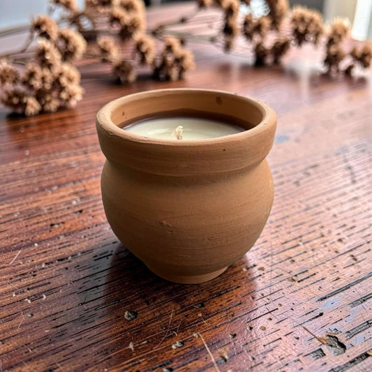 Ceramic pot with a candle on a wooden surface