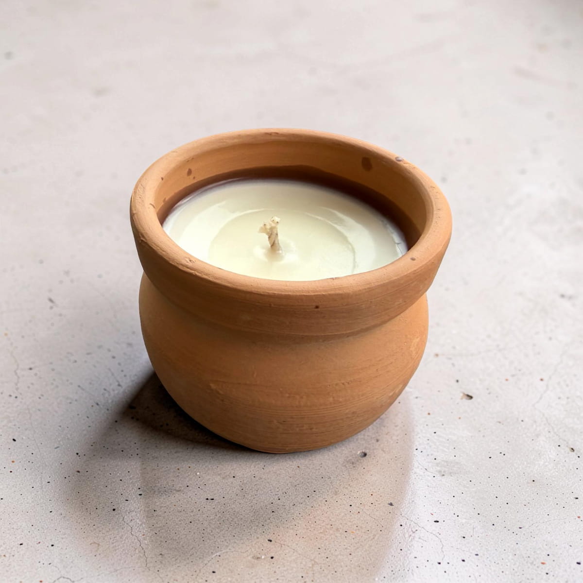 Candle in a terracotta pot on a light surface