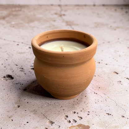 Candle in a terracotta pot on a textured surface