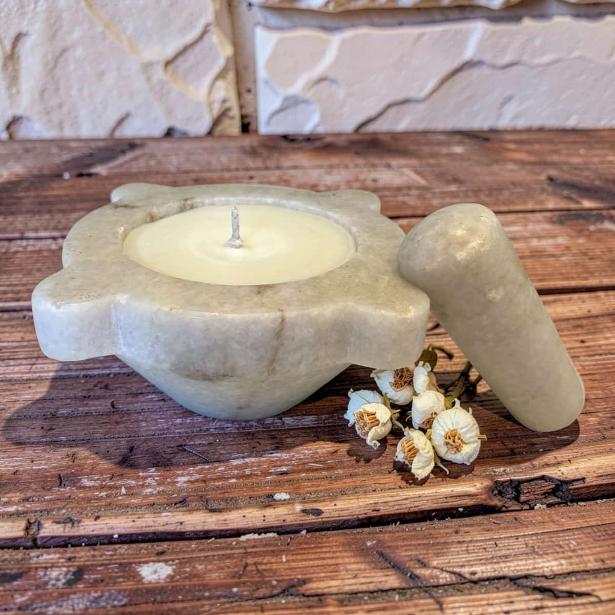 Candle in a stone holder on a wooden surface with dried flowers