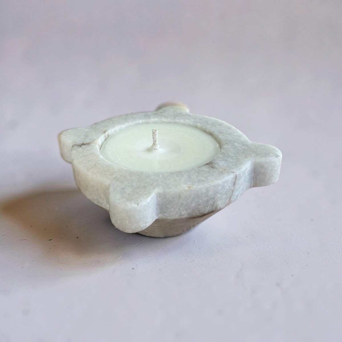 Candle in a stone holder on a light gray background