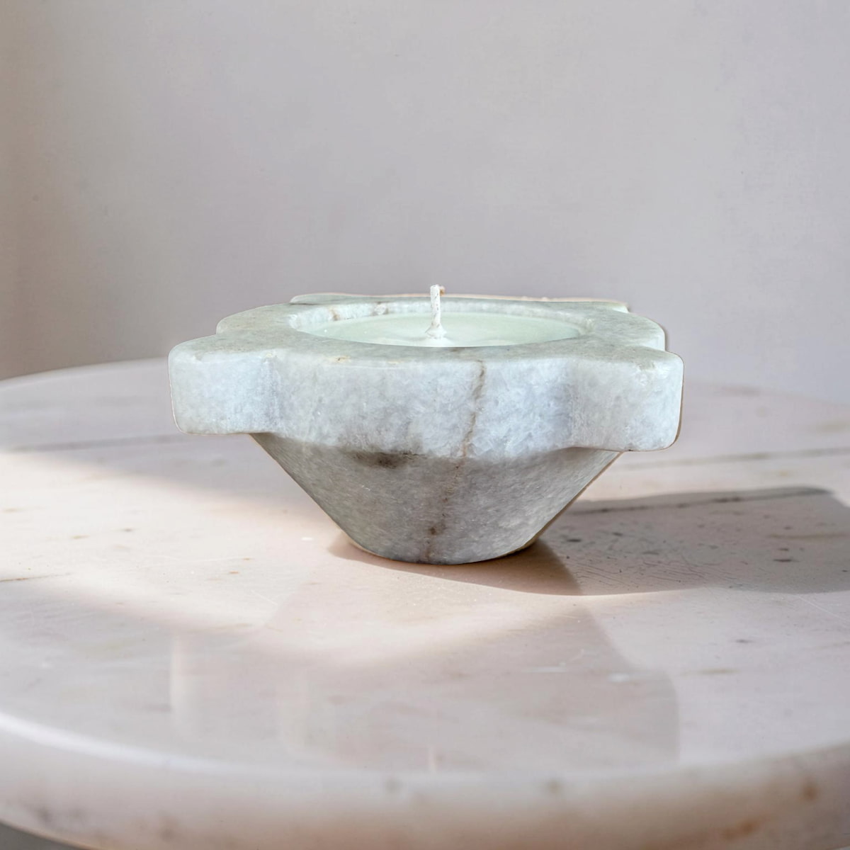 Marble candle holder with a candle on a marble surface