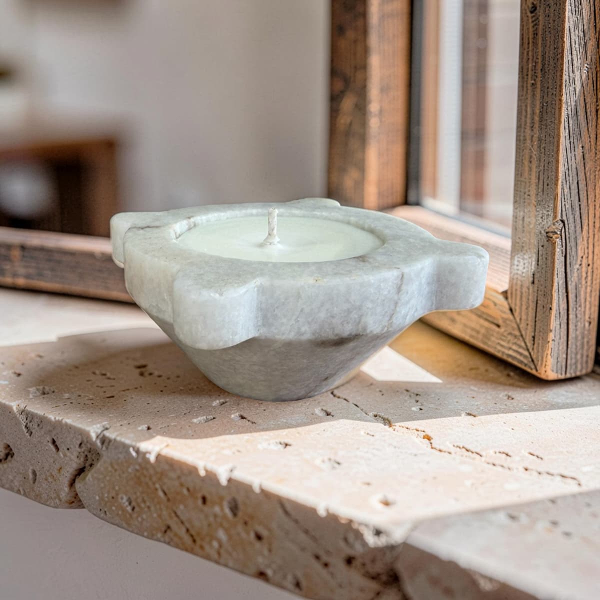 Candle in a stone holder on a stone surface with a wooden frame in the background