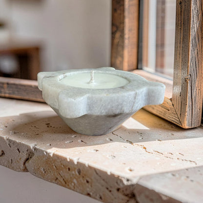 Candle in a stone holder on a stone surface with a wooden frame in the background