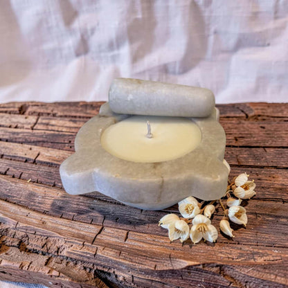 Candle in a stone holder on a wooden surface with white flowers