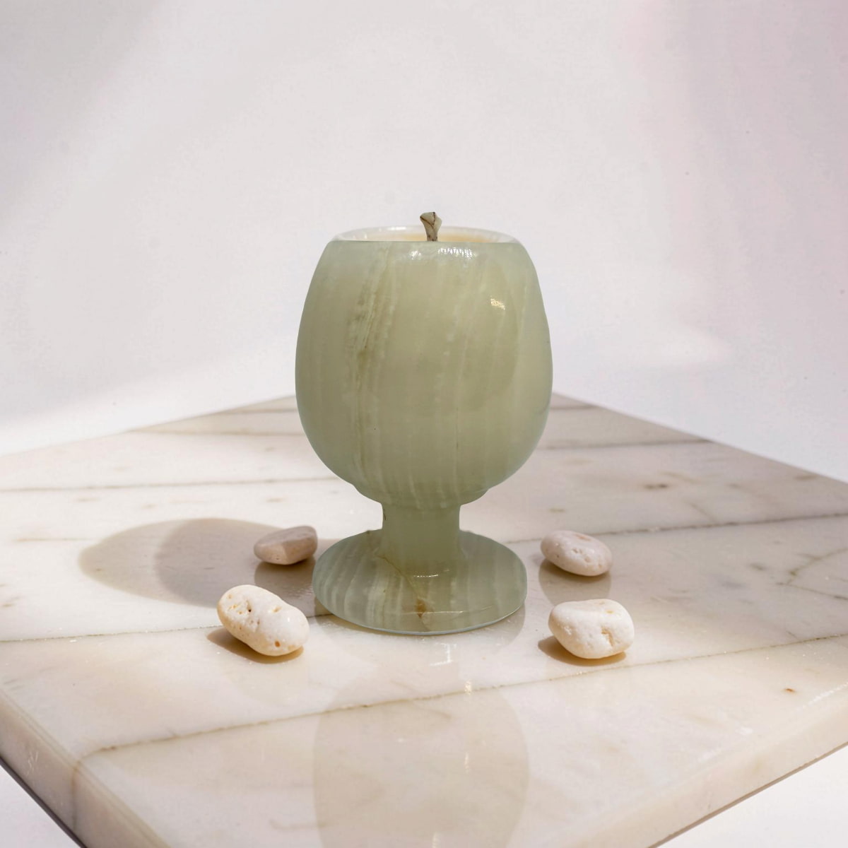 Green ceramic goblet on a wooden surface with small stones around it