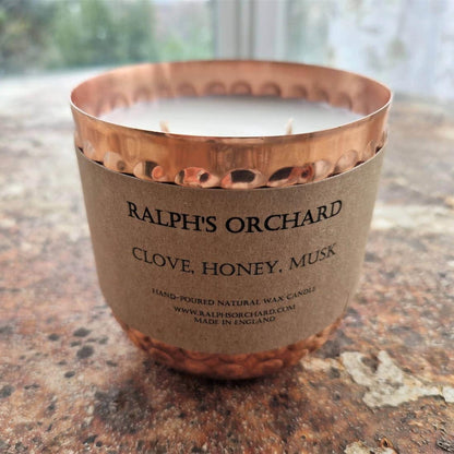 Candle with a copper lid and kraft paper label on a stone surface