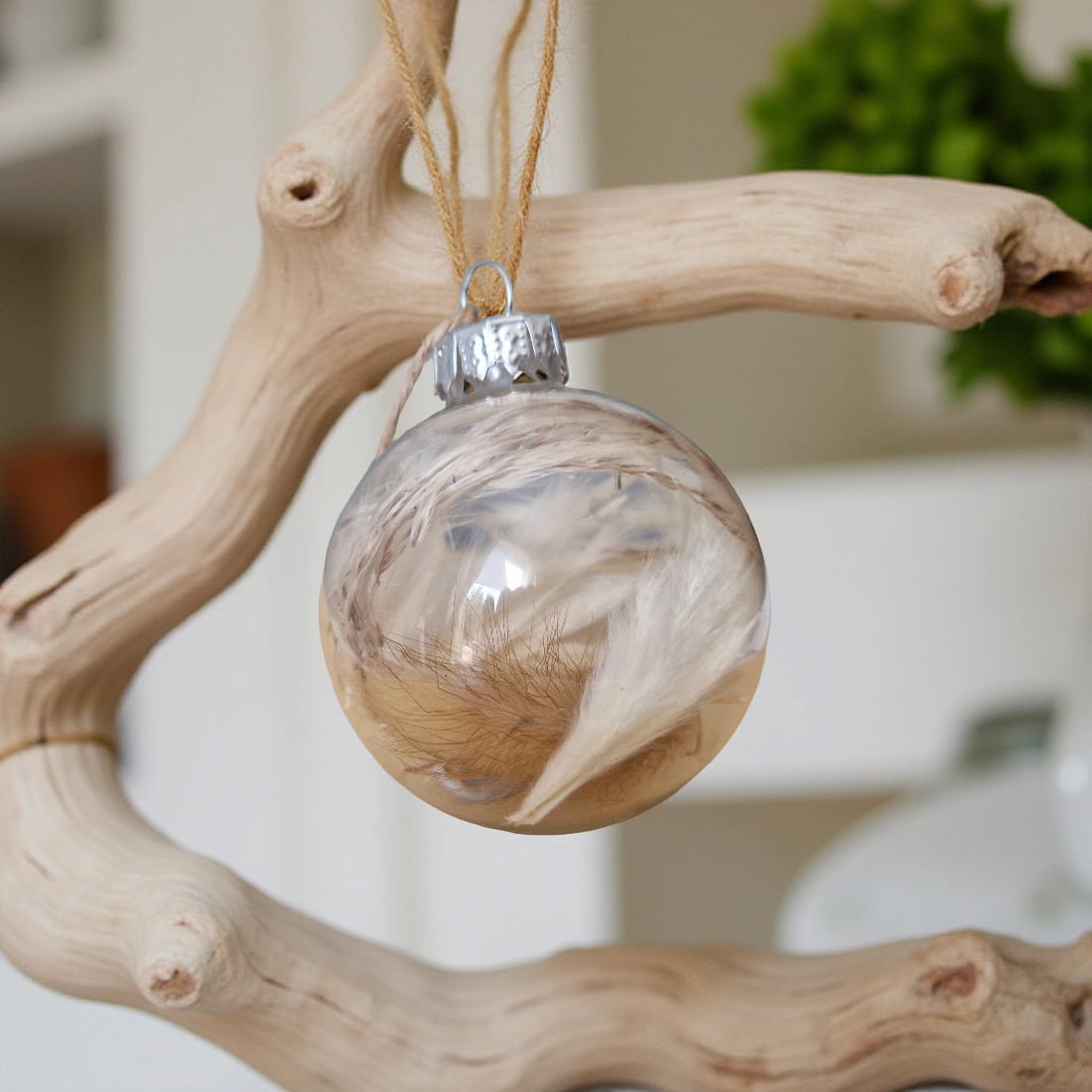 Decorative glass ball ornament with wooden finish hanging on a branch.