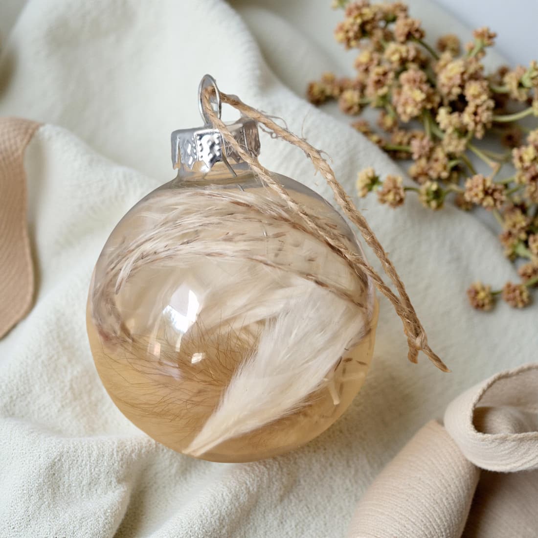 Decorative glass ornament with natural elements on a soft fabric background