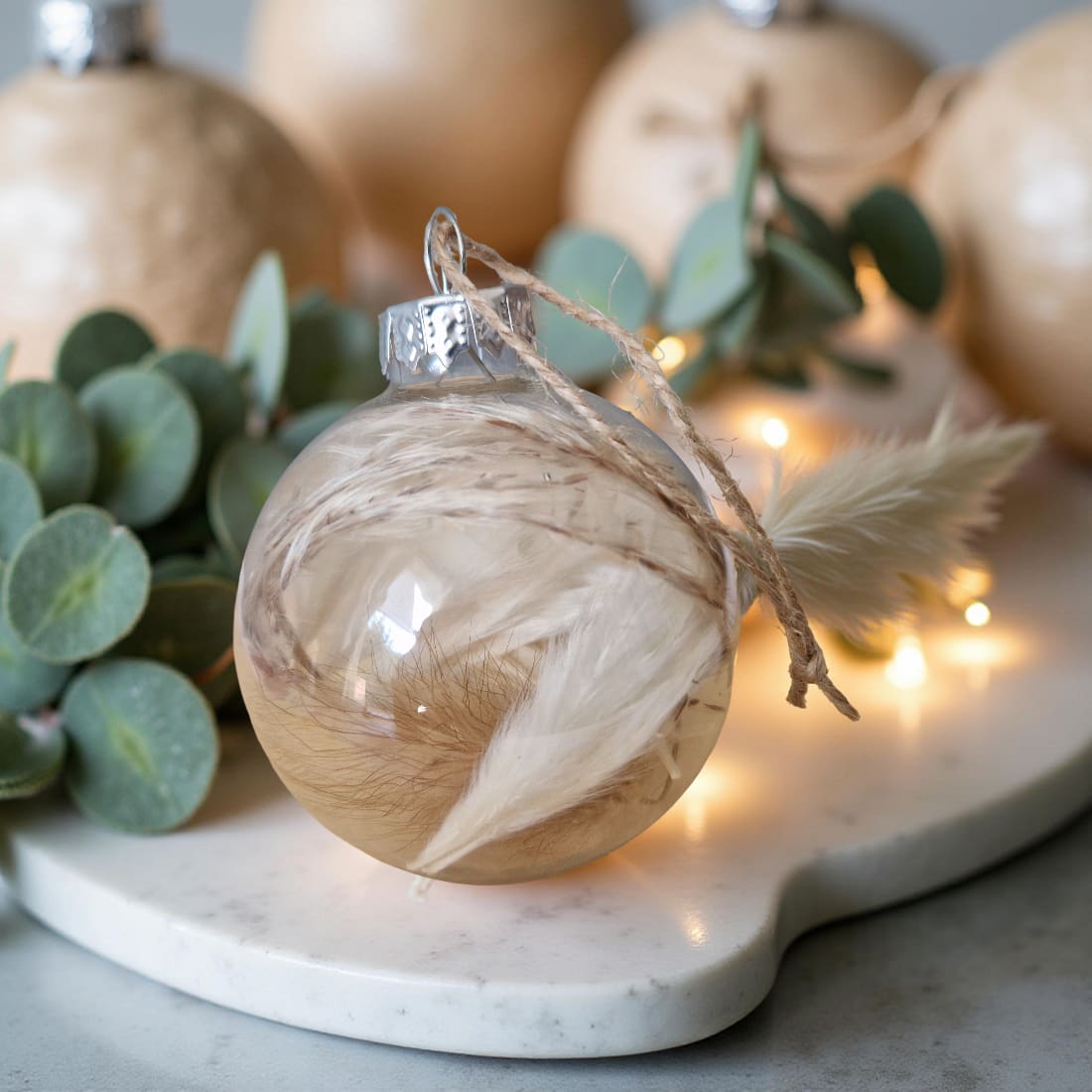 Decorative ornament with wooden finish and eucalyptus leaves on a marble surface with lights in the background