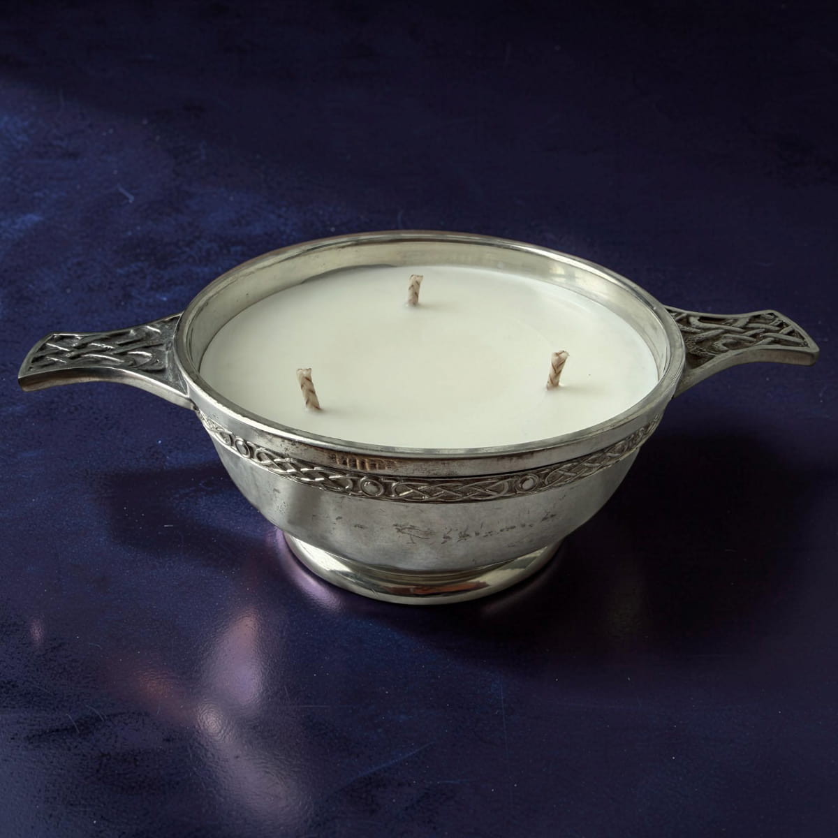 Decorative candle in a silver holder on a dark blue background