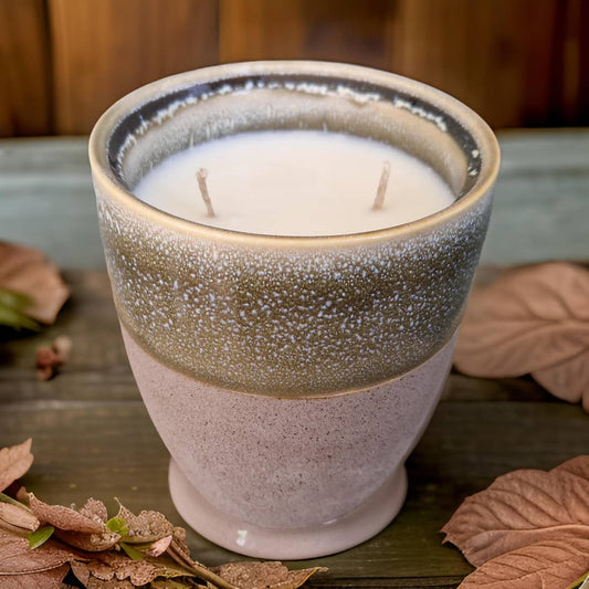 Ceramic candle holder with a candle on a wooden surface with leaves