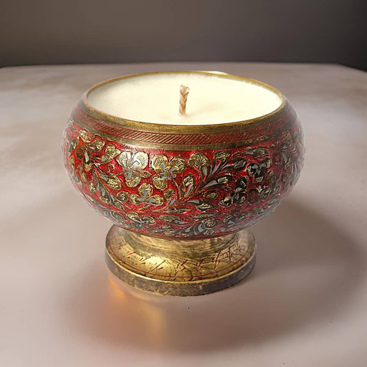 Decorative candle in a red and gold holder on a neutral background