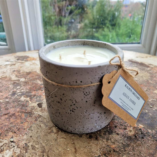 Ceramic candle with a wooden tag on a textured surface