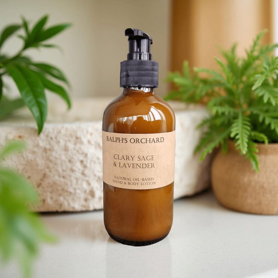 Amber bottle with pump labeled 'Ralph's Orchard Clary Sage & Lavender Lotion' on a neutral background with plants.