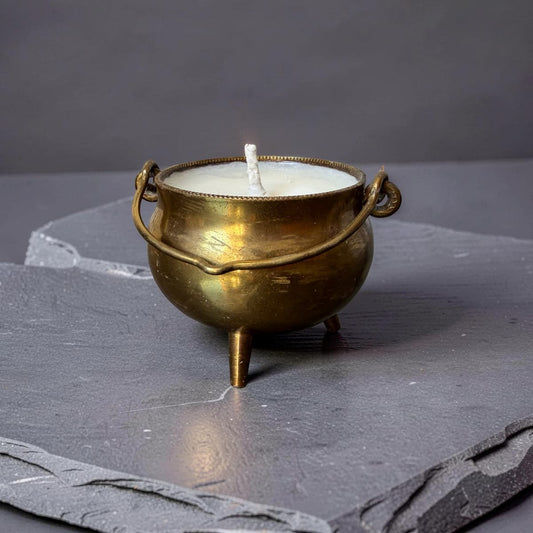 Brass cauldron-shaped candle on a dark surface
