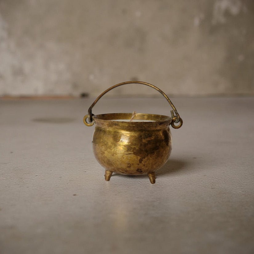 Small brass cauldron on a plain surface with a neutral background