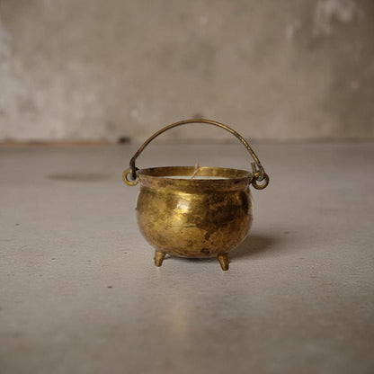 Small brass cauldron on a plain surface with a neutral background