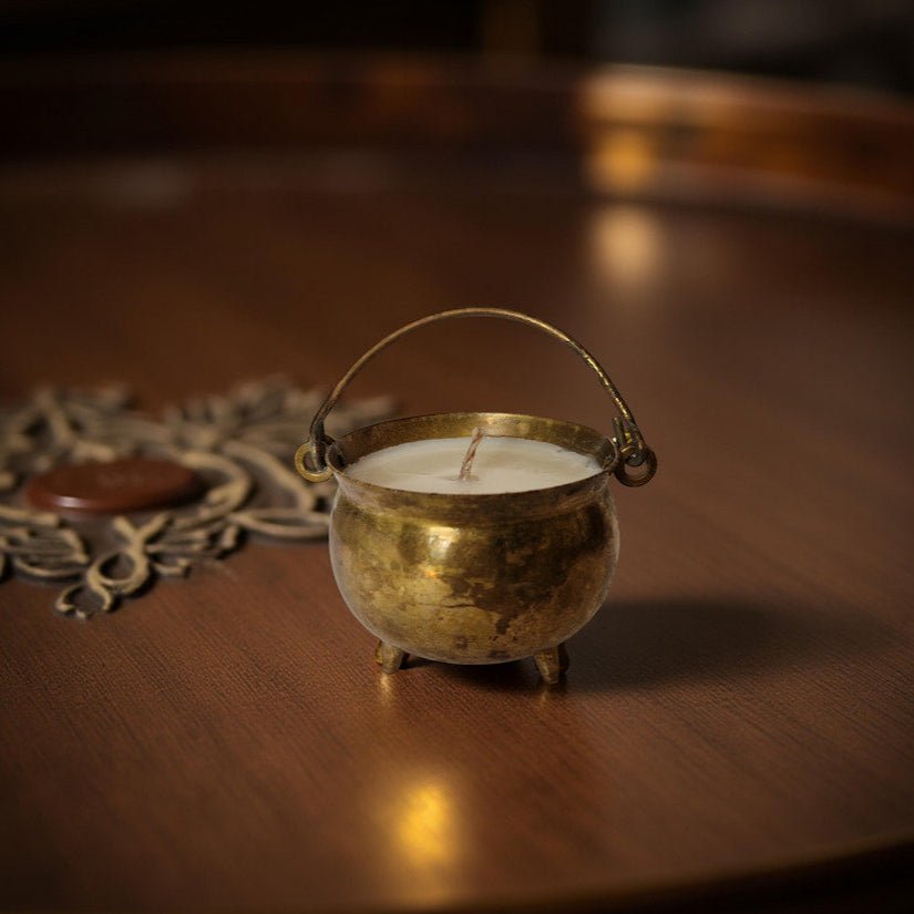 Small brass container with a candle on a wooden surface