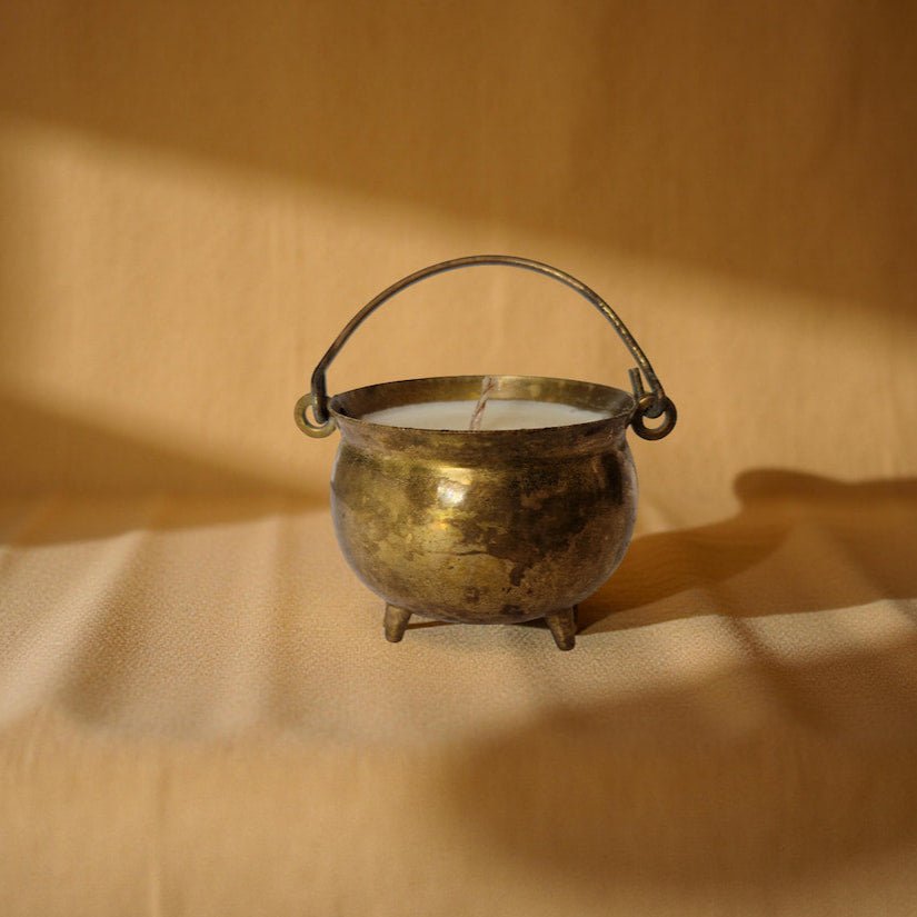 Brass candle holder with a candle on a beige surface