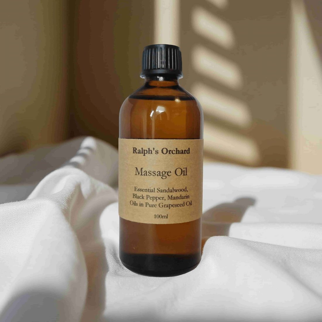 Bottle of Ralph's Orchard Massage Oil on a white surface with a neutral background
