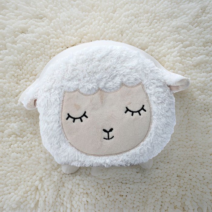 White sheep-shaped cushion with a face on a beige textured background