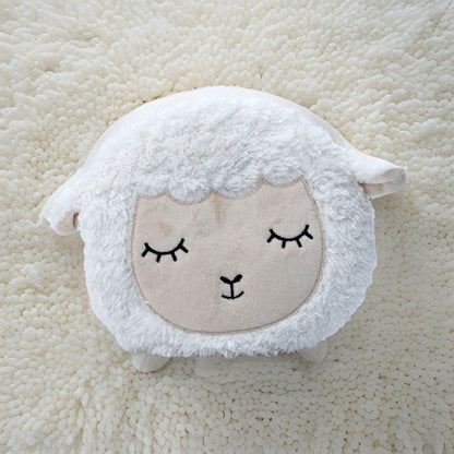 White sheep-shaped cushion with a face on a beige textured background