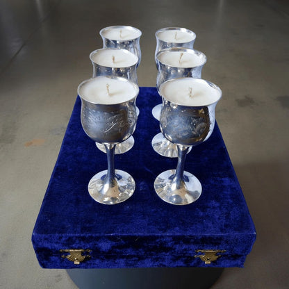 Silver candle holders with candles on a blue velvet box against a gray background