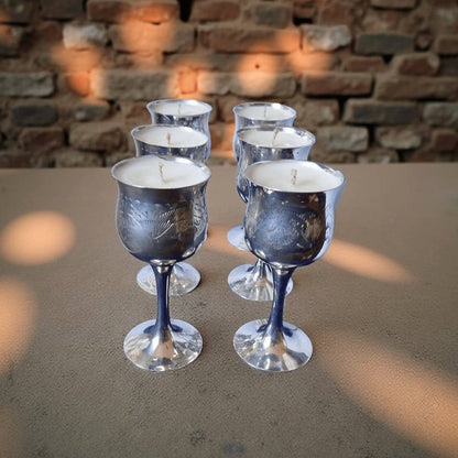 Silver wine glass candles on a stone surface with a brick wall background
