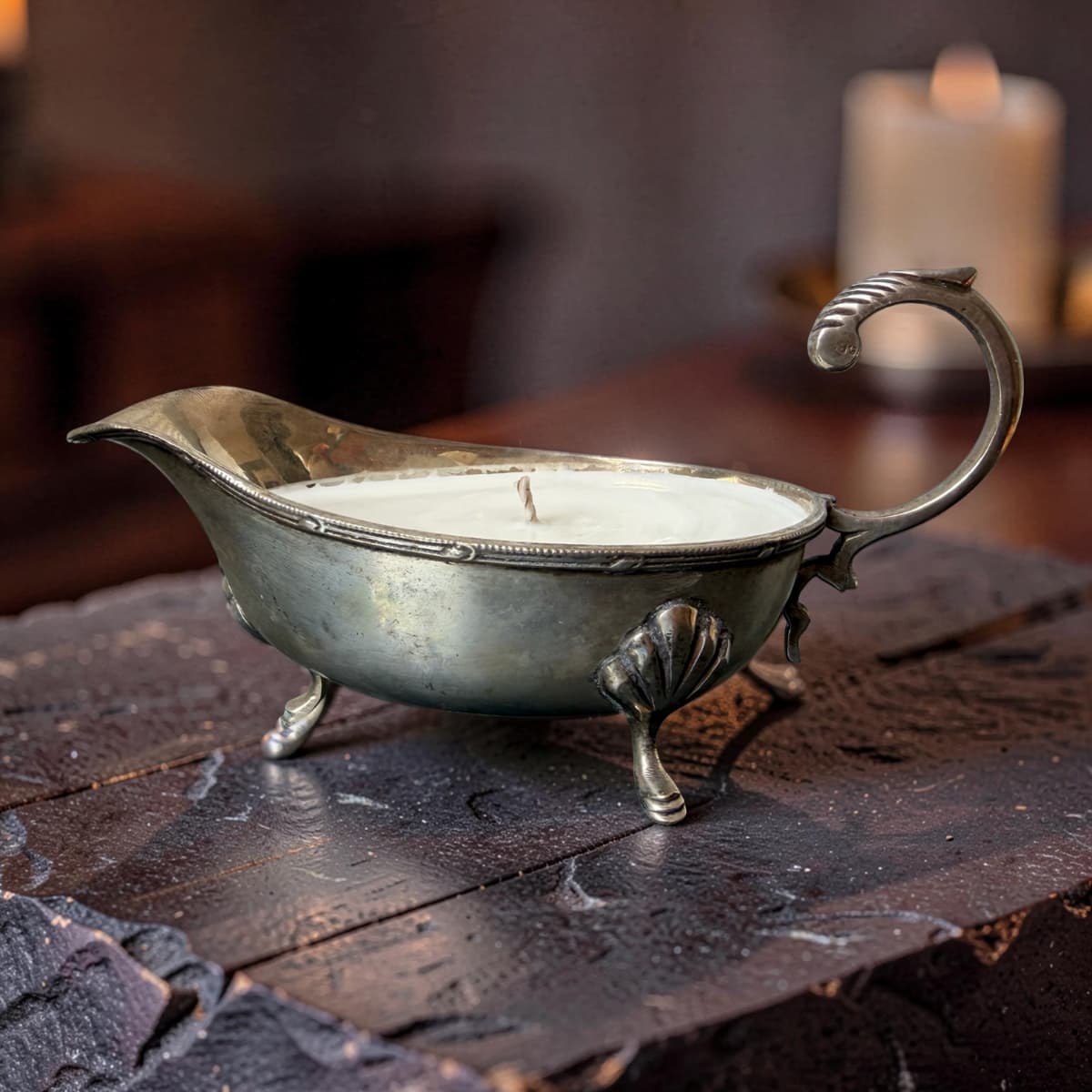 Decorative metal candle holder on a wooden surface with a blurred candle in the background.
