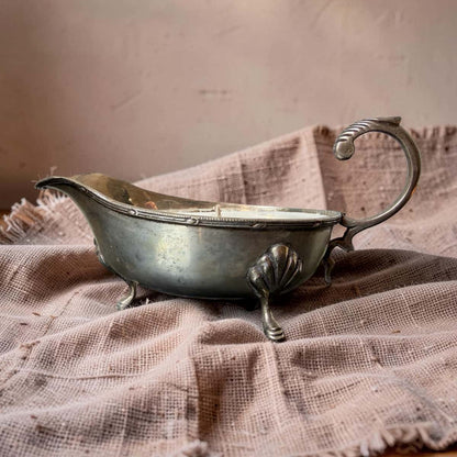 Silver gravy boat on a textured fabric background
