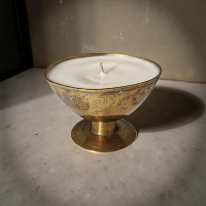Candle in a decorative brass holder on a concrete surface