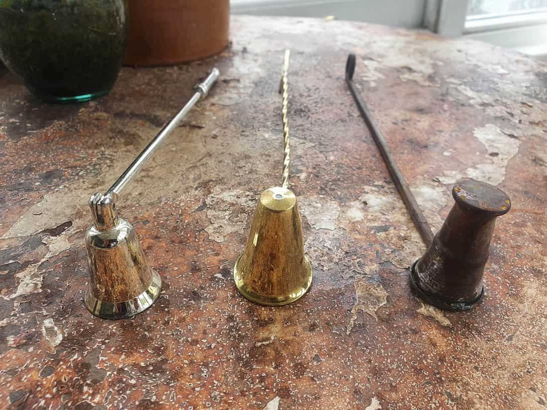 Three vintage-style candle snuffers on a marble surface
