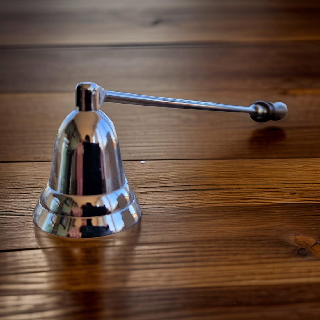 Metallic candle snuffer on a wooden surface