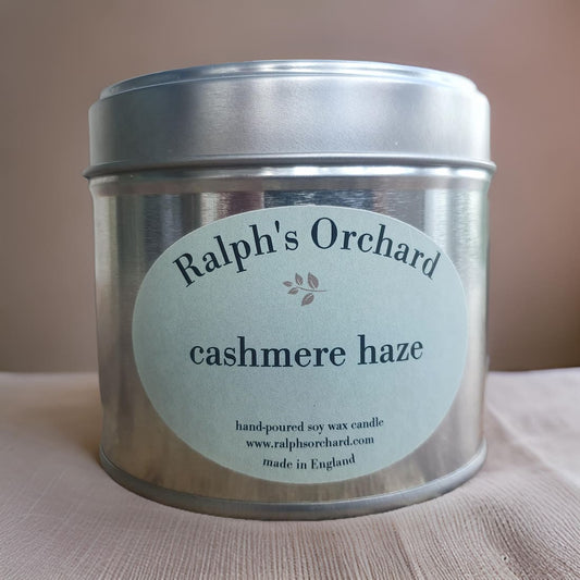 Candle tin labeled 'Ralph's Orchard cashmere haze' on a beige background